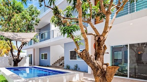 Un edificio moderno con piscina, escaleras exteriores y un árbol.