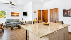Una sala de estar moderna con una isla grande, un sofá y un televisor de pantalla plana.