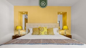A hotel room with a large bed, two bedside lamps, and a headboard with a mirror. - Amazing 1 BR Condo in Romantic Zone - Rooftop Pool (Puerto Vallarta)