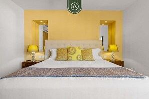 A hotel room with a bed, two bedside lamps, a headboard, and a large mirror. - Amazing 1 BR Condo in Romantic Zone - Rooftop Pool (Puerto Vallarta)
