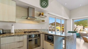 A modern kitchen with granite countertops, stainless steel appliances, and a large island. - Amazing 1 BR Condo in Romantic Zone - Rooftop Pool (Puerto Vallarta)