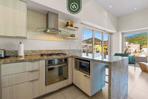 A modern kitchen with granite countertops, stainless steel appliances, and a large island. - Amazing 1 BR Condo in Romantic Zone - Rooftop Pool (Puerto Vallarta)