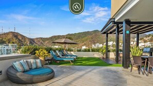 A rooftop patio with a circular seating area, a dining table, and a grill. - Amazing 1 BR Condo in Romantic Zone - Rooftop Pool (Puerto Vallarta)