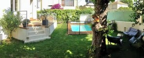 Un jardin avec une piscine, un petit escalier et un hamac.