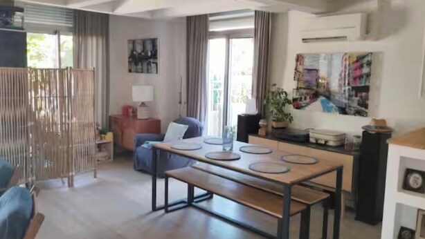 Un amplio espacio habitable con una gran mesa de madera, un sofá y una mesa de comedor con sillas.