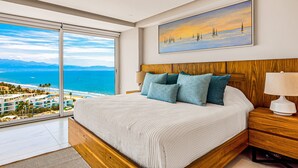 Ein Schlafzimmer mit einem großen Fenster, einem Bett mit einem Holz-Kopfteil und einem Gemälde mit Segelbooten.