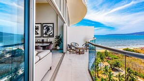 Ein Balkon mit Blick auf das Meer, eine Couch, ein Esstisch und Stühle.