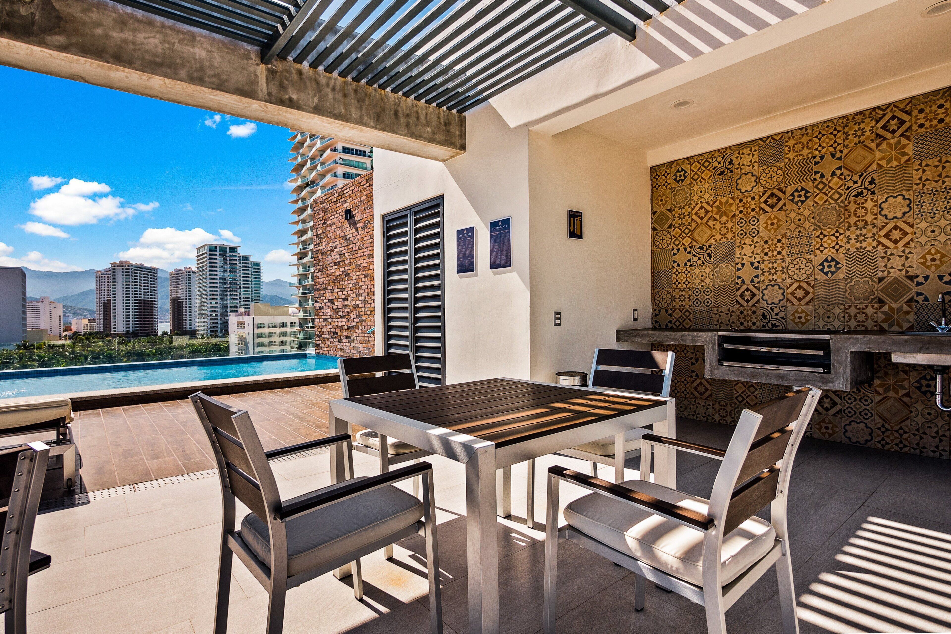 A rooftop terrace with a pool view, a dining table with chairs, and a patterned backsplash.