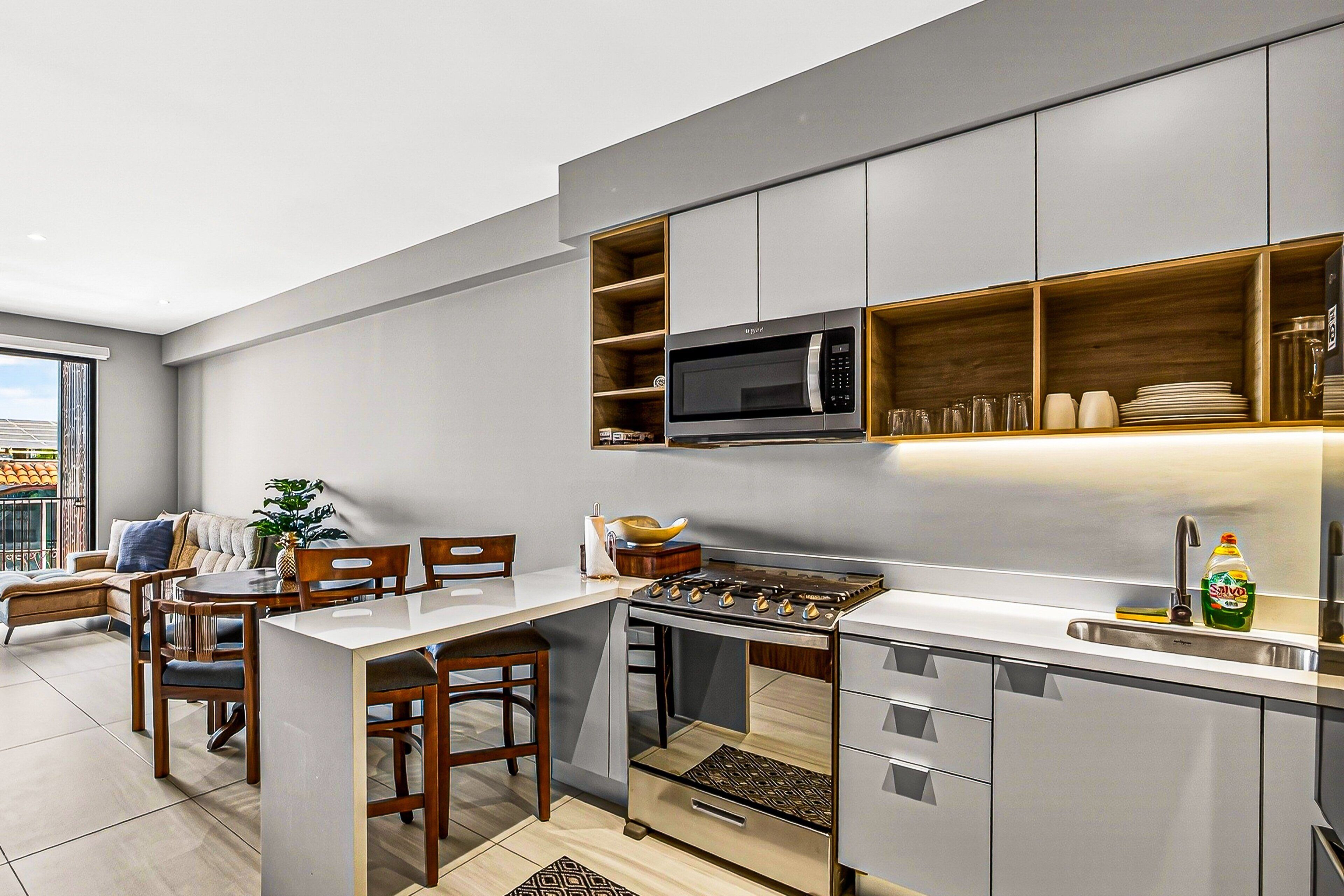 Una cocina moderna con microondas integrado, estufa y repisas de madera.