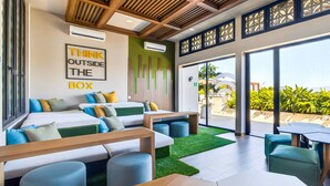 A modern hotel room with a large bed, seating area, and a view of the outdoors. - Modern Condo With Rooftop Pool, Balcony, gas Grill & gym Access (Puerto Vallarta)