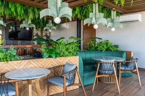 Ein Restaurant mit Holzboden, grünen Polstersitzen und hängenden Pflanzen.