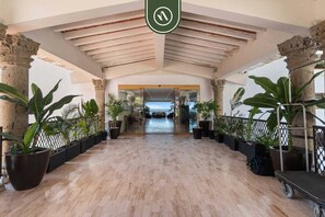 A hotel lobby with a wooden floor, columns, and potted plants. - Peaceful Oceanview -costa Sur Estudio 8 (Puerto Vallarta)