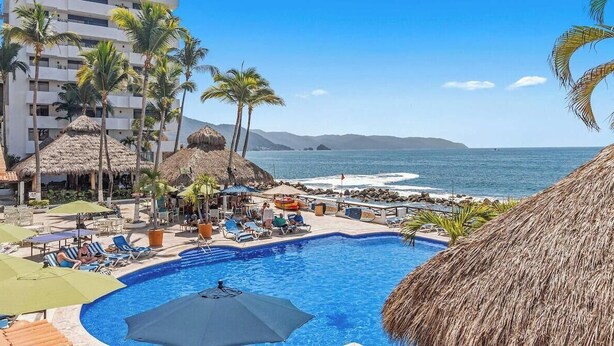 A pool area with lounge chairs, umbrellas, and a view of the ocean. - Peaceful Oceanview- Costa Sur Estudio 1 (Puerto Vallarta)