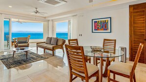 A spacious living area with a glass table, wooden chairs, a sofa, and a view of the ocean. - Stunning 7th-floor Condo With Outdoor Pool, hot tub & bay Views (Puerto Vallarta)