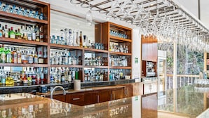 Een bar met flessenkast vol drank, een gepolijst granieten aanrecht en een moderne kroonluchter.