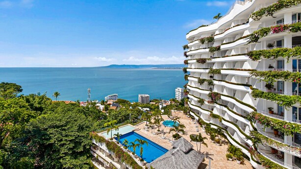 A hotel with a pool, lush greenery, and a view of the sea. - Stylish Oceanview Suite With Infinity Pool, Full Kitchen & Bay-view Terrace (Puerto Vallarta)