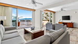 A modern hotel room with a balcony, a flat-screen TV, and a seating area with a coffee table. - Stylish Oceanview Suite With Infinity Pool, Full Kitchen & Bay-view Terrace (Puerto Vallarta)