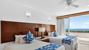 A hotel room with two beds, a wooden headboard, a ceiling fan, and a balcony with a view of the ocean. - Stylish Oceanview Suite With Infinity Pool, Full Kitchen & Bay-view Terrace (Puerto Vallarta)