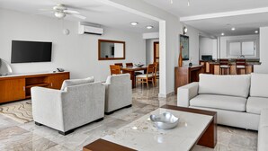 A modern living room with a sofa, armchairs, a coffee table, and a TV. - Stylish Oceanview Suite With Infinity Pool, Full Kitchen & Bay-view Terrace (Puerto Vallarta)
