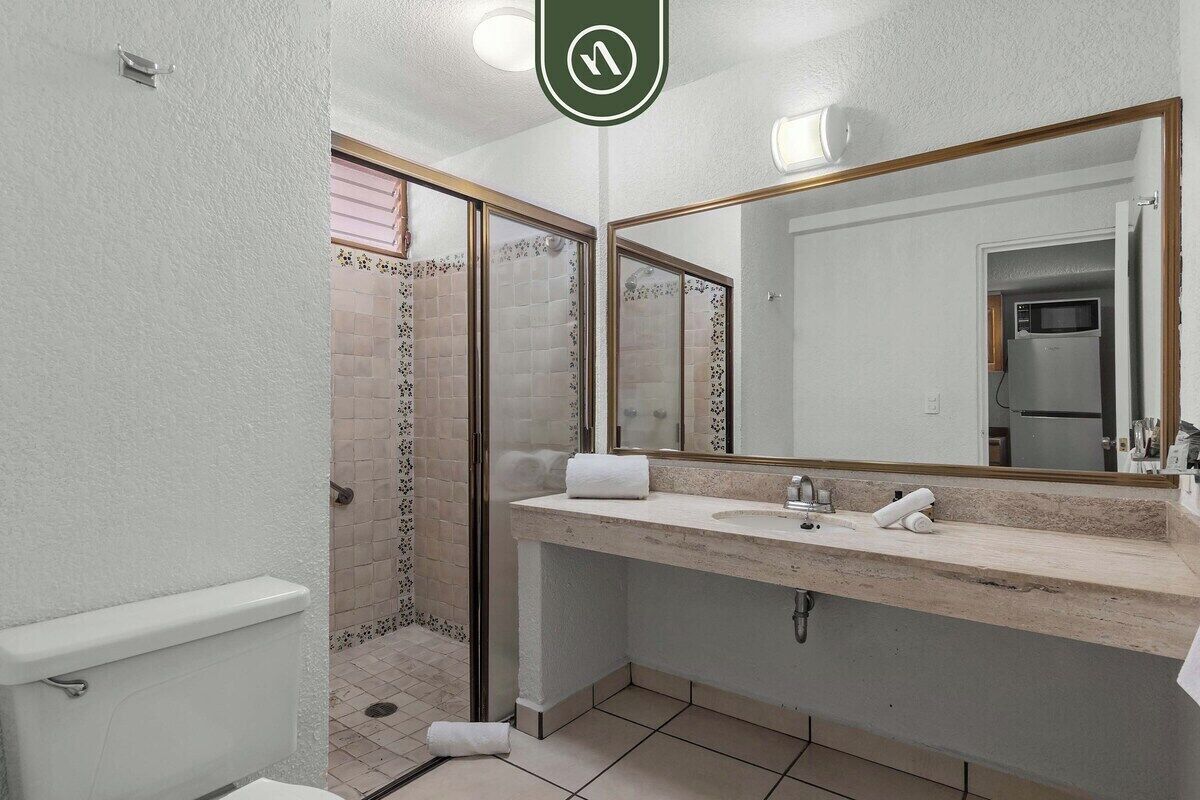A bathroom with a toilet, sink, and shower area.