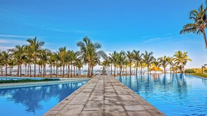 A long, straight swimming pool with a clear blue sky above, surrounded by palm trees. - Oceanfront Luxury With Amazing View, 4 Pools, Private Beach, On-site Spa, Dining (Nuevo Nayarit)