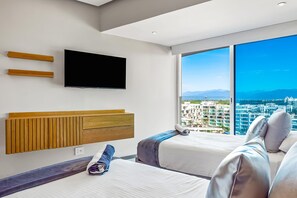 Een moderne hotelkamer met een groot raam, een flatscreen televisie, een houten hoofdbord en twee bedden met kussens.