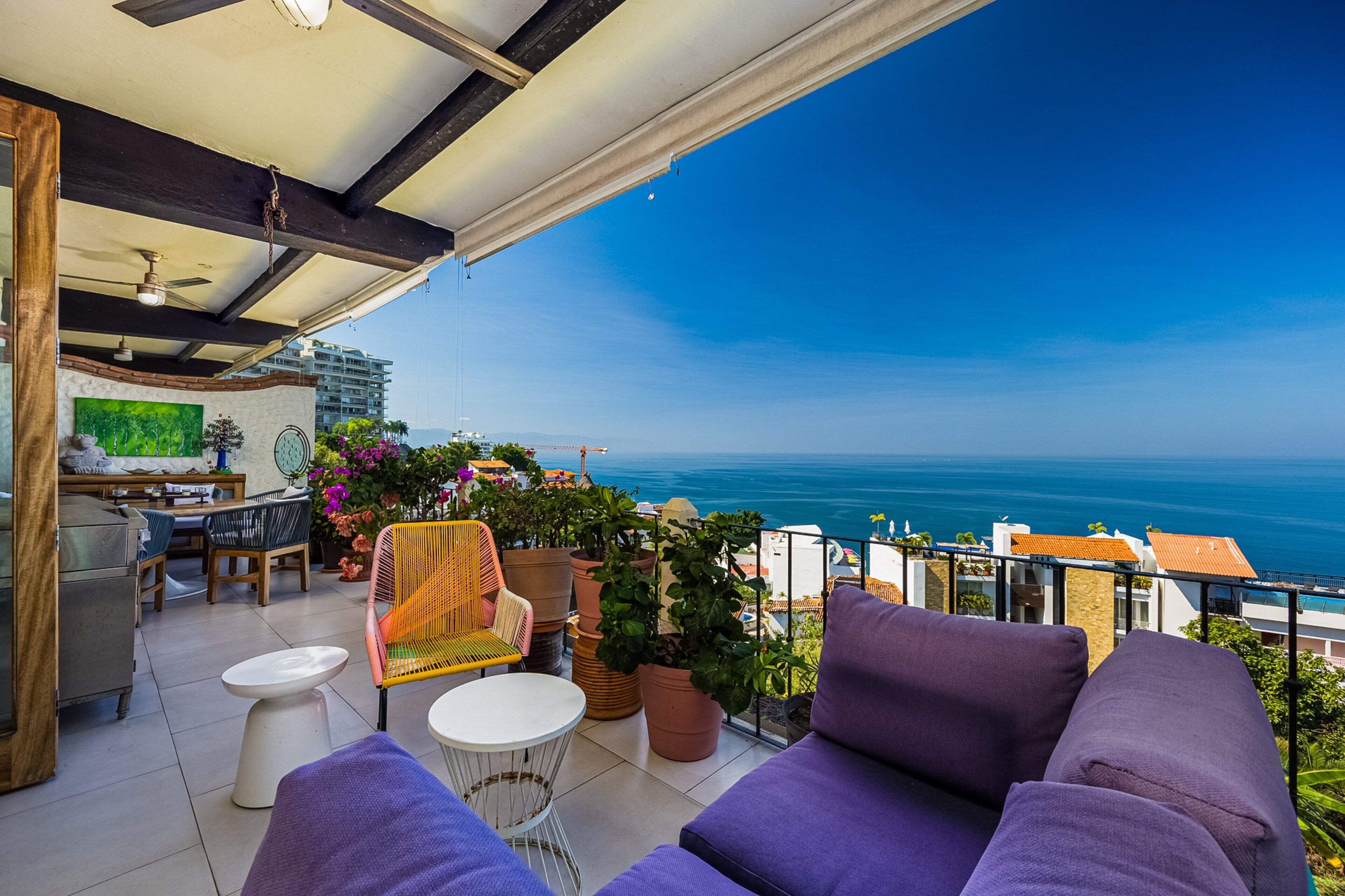 Un balcón con vistas al mar, una zona de comedor con sillas y una mesa, y un sofá.