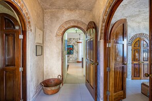 A hallway with wooden doors, a stone wall, and a tiled floor. - Charming Condo Featuring Ocean Views, Pool & Private Terrace (Puerto Vallarta)
