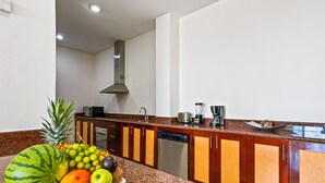 Cuina amb encimera de granit, armaris de fusta, rentaplats d'acer inoxidable i un plat de fruita.