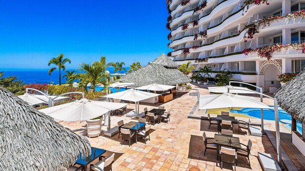 Un complex turístic amb zona de piscina, mobiliari exterior i vistes a l'oceà.