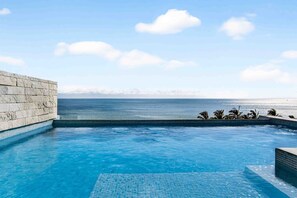 A swimming pool with a view of the ocean and a stone wall. - Relaxing Condo With Rooftop Pool, Oceanview Balcony & Walkable Beach Access (Bucerías)