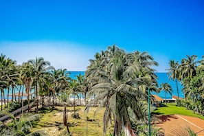Un resort tropical con palmeras, piscina y vista al océano.