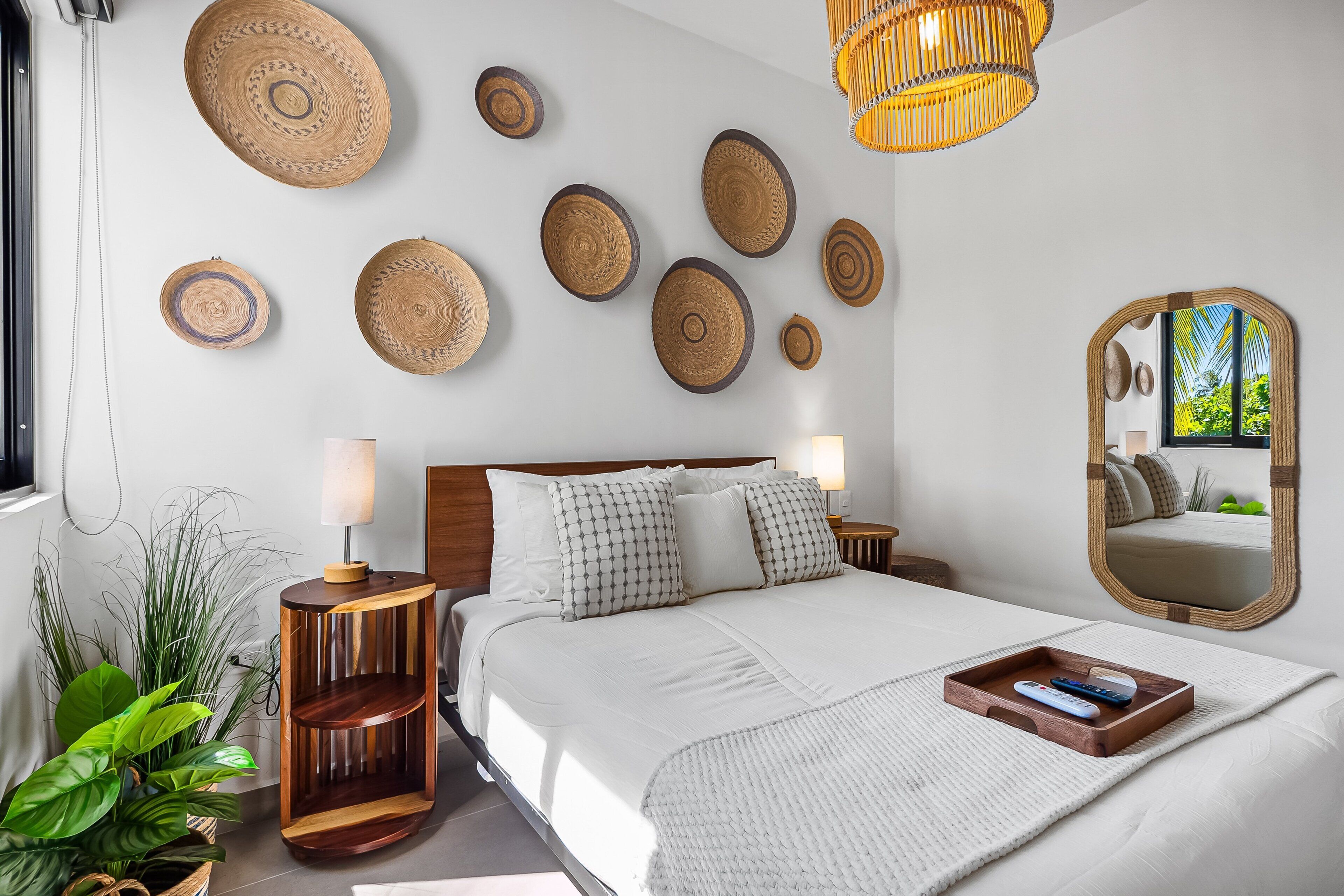 A modern bedroom with a bed, bedside tables, a mirror, and decorative wall plates.