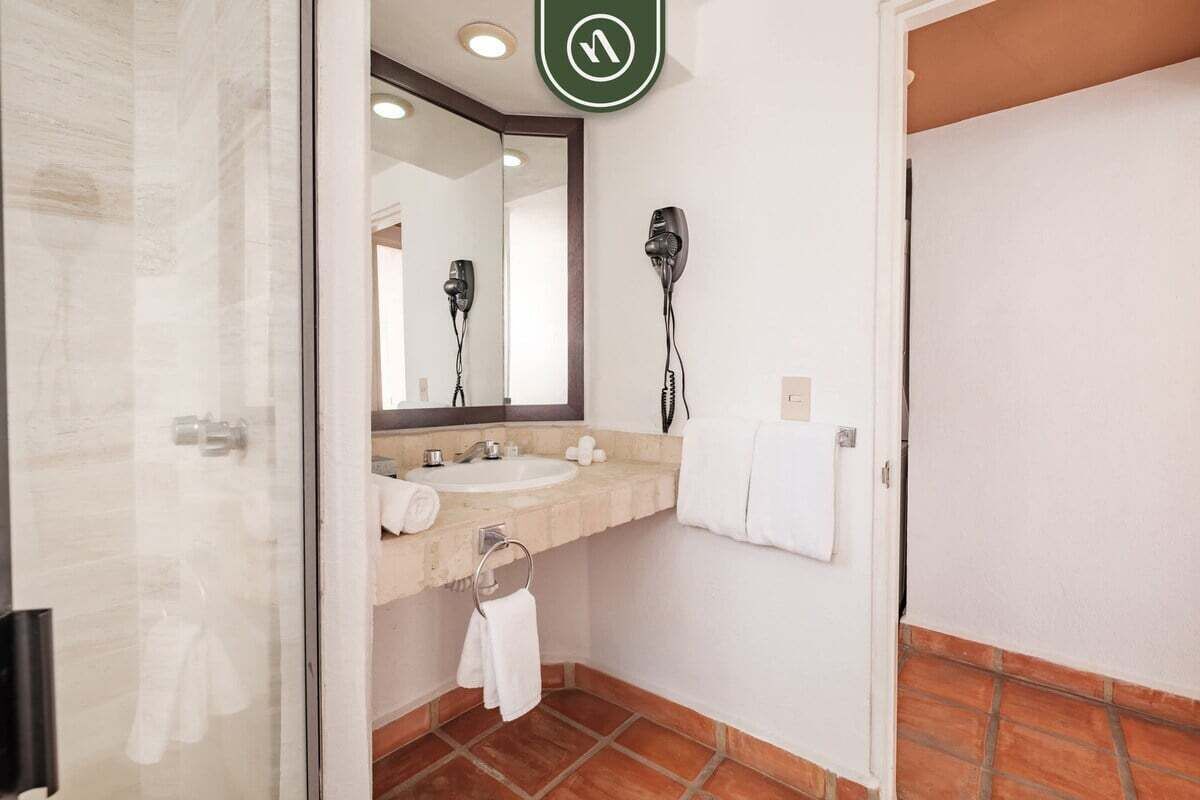 Une salle de bain équipée d’un miroir, d’un lavabo et de deux sèche-cheveux.