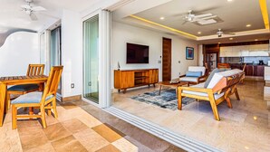 A spacious living area with a dining table, chairs, sofas, a TV, and a kitchen in the background. - Lavish Seaside Escape With Oceanfront Views, Amazing Pool & Pool spa (Puerto Vallarta)