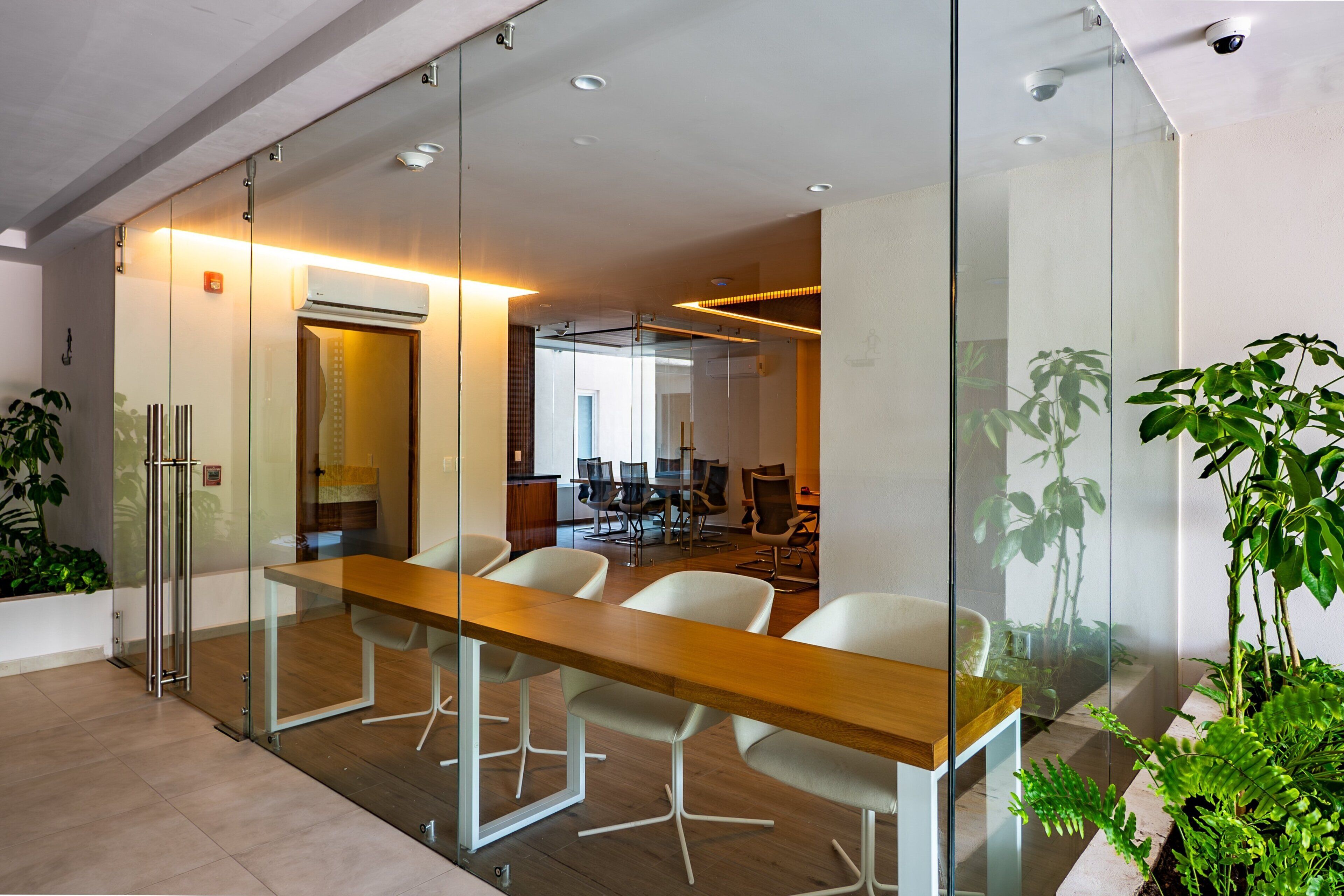 A conference room with a glass partition, a wooden table, and white chairs.