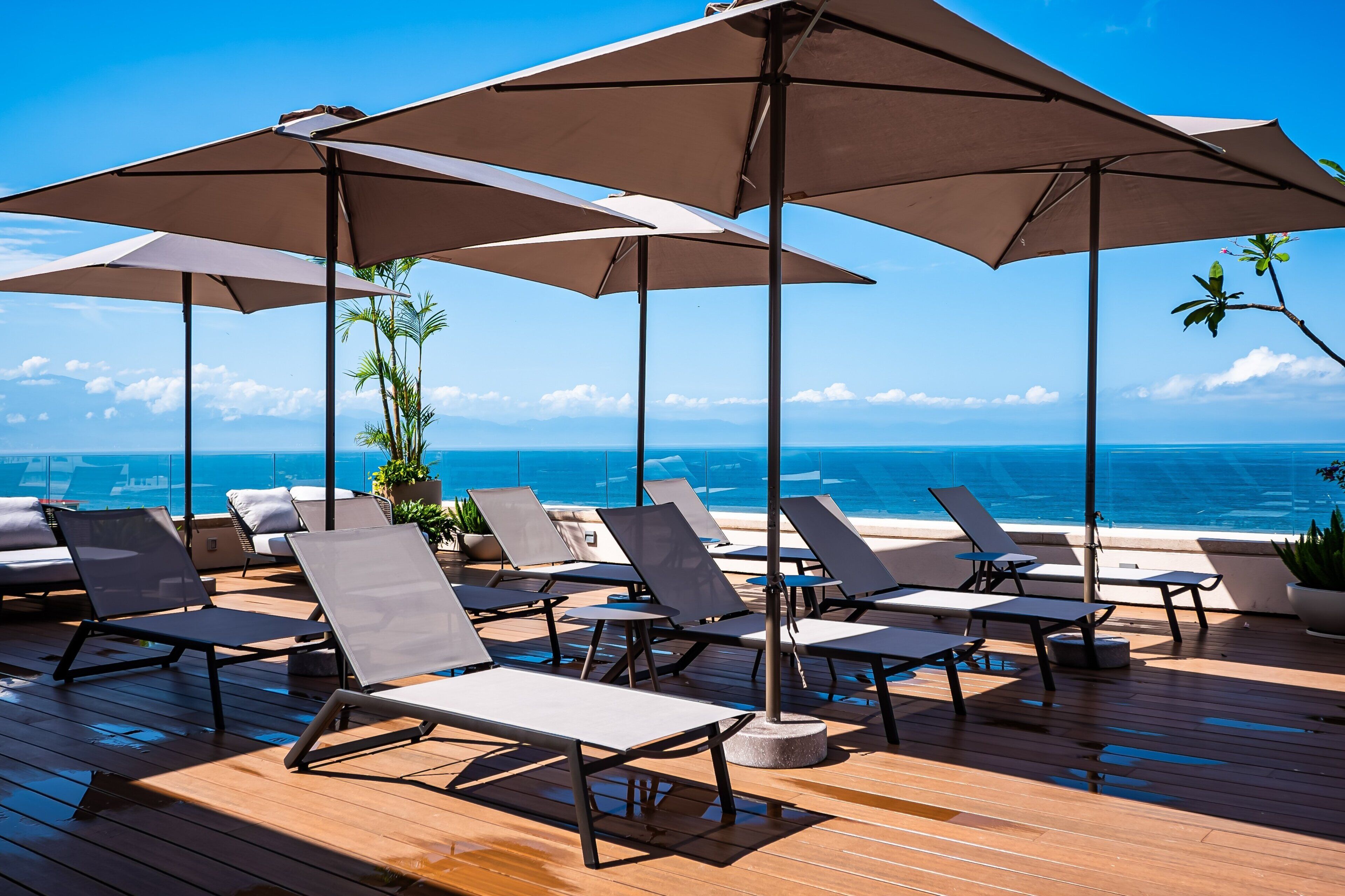 Une terrasse avec des chaises longues et des parasols, donnant sur une plage.
