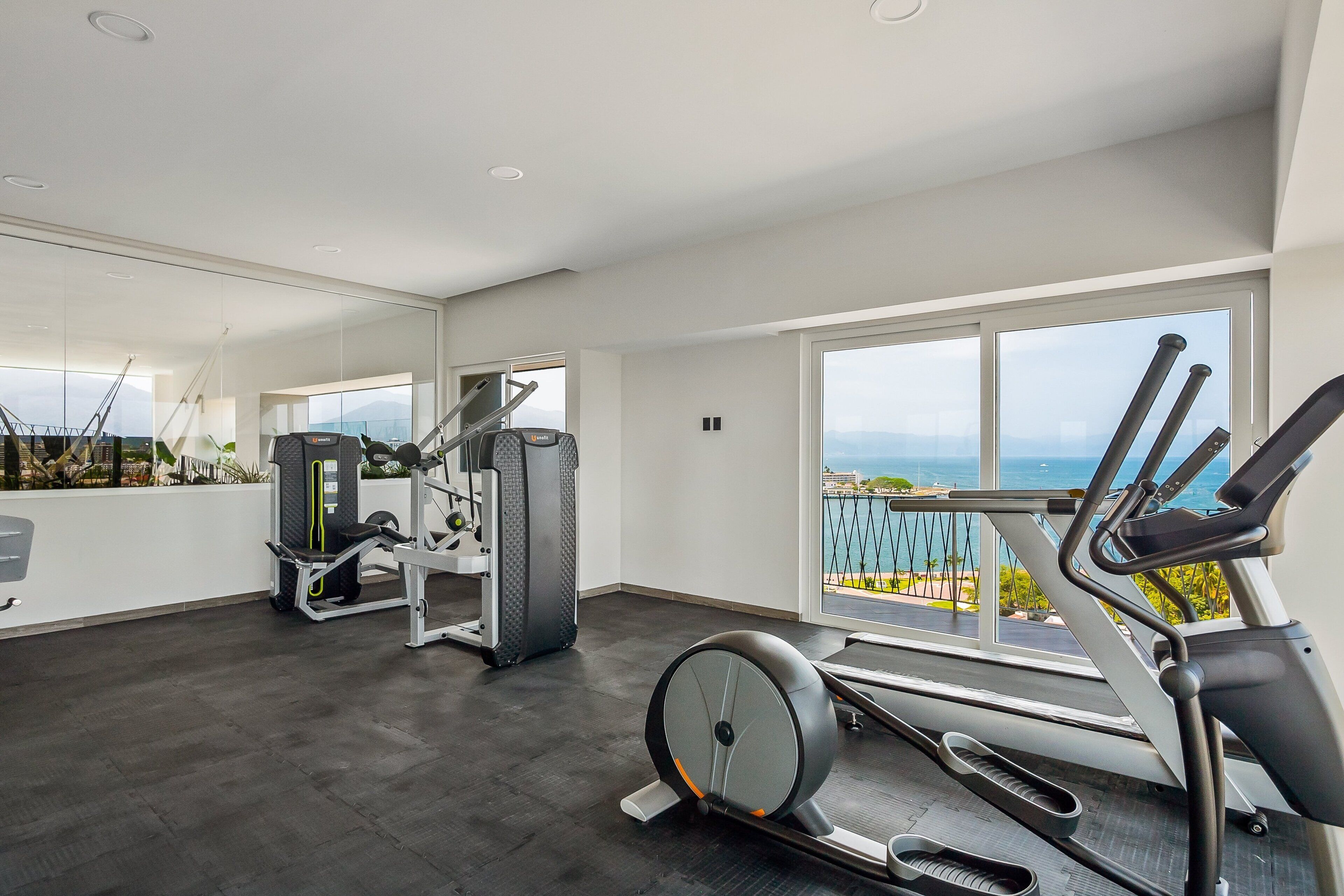 Una palestra con attrezzi, ampie finestre e vista sull'esterno.