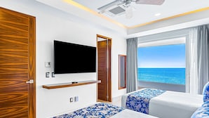 A room with a TV, two beds with patterned bedding, a wooden wardrobe, and a view of the sea. - Dreamy Coastal Condo With Amazing Ocean Views, Pool & Pool spa (Puerto Vallarta)