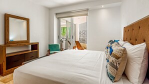 A bedroom with a large bed, a wooden dresser, a mirror, and a view of a balcony. - Nitta Condo # 104 Chic, Pool-view Condo With Furnished Balcony - Steps to Beach (Nuevo Nayarit)
