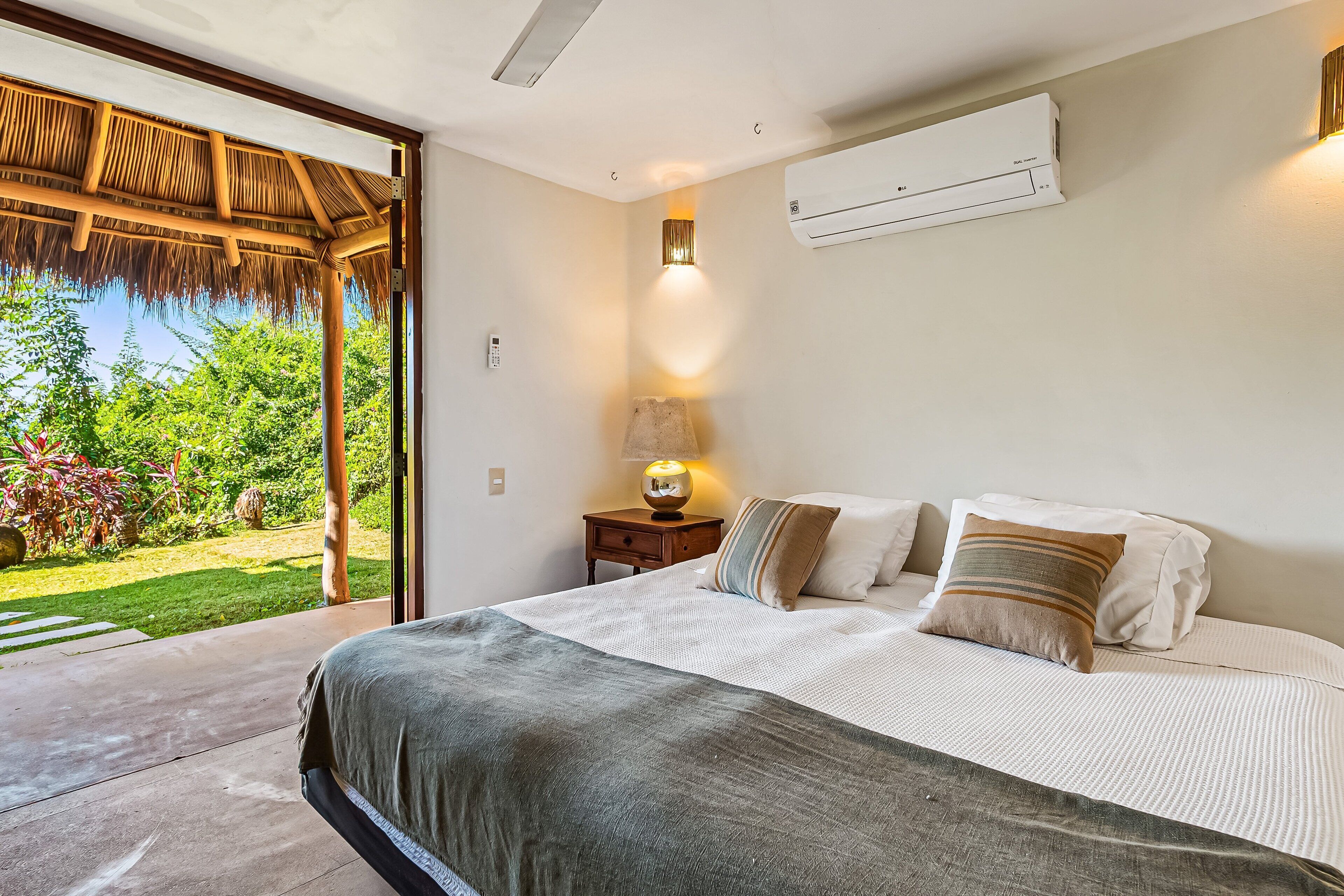 Un dormitorio con cama, mesita de noche, lámpara y aire acondicionado.
