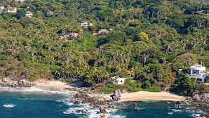 Una zona costera con casas rodeadas de vegetación exuberante y una playa.