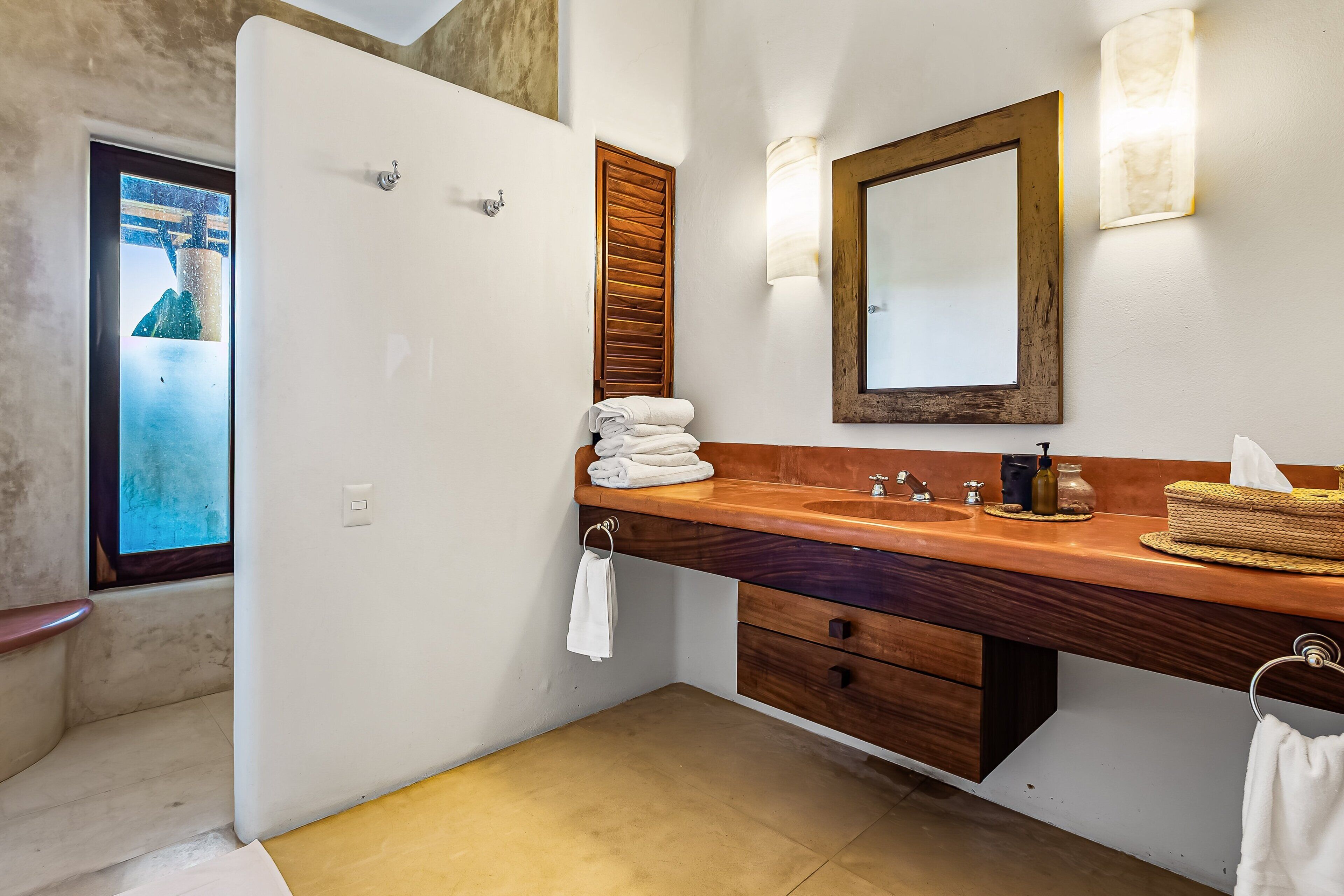 A bathroom with a wooden vanity, a mirror, a towel rack, and a view of a mountain through a window.