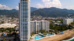 Ein Hochhaus-Hotel mit mehreren Etagen, einem Poolbereich und Blick auf den Strand.