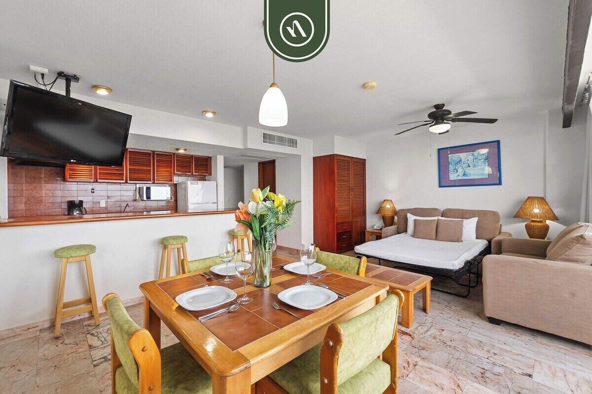 Habitación de hotel compacta con comedor, kitchenette y cama.