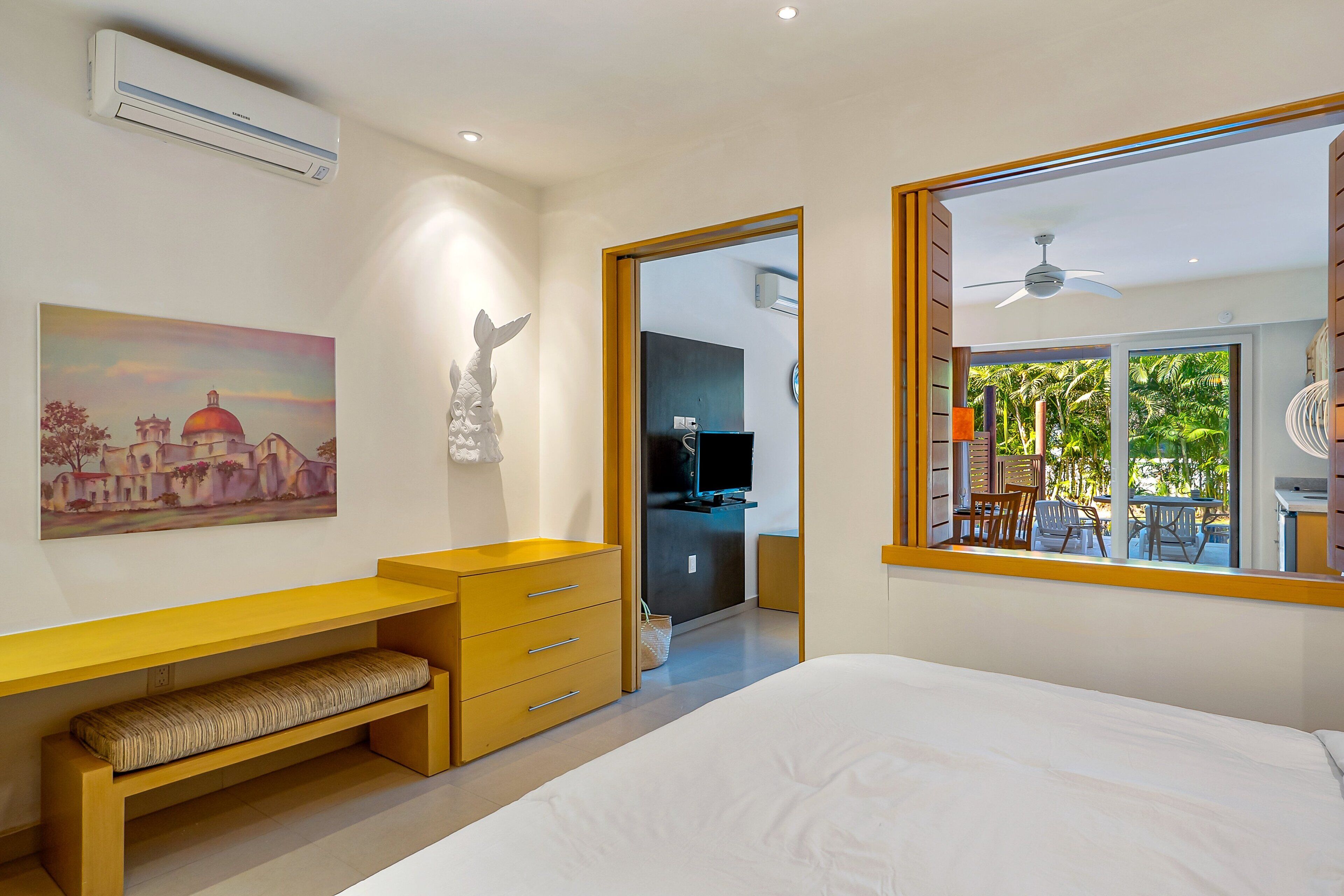 Een moderne slaapkamer met een bed, een bureau, een stoel, een televisie en een balkon met tuinmeubilair.