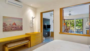 Een moderne slaapkamer met een bed, een bureau, een stoel, een televisie en een balkon met tuinmeubilair.