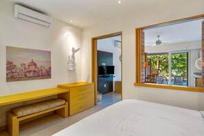 A modern bedroom with a bed, a desk, a chair, a television, and a balcony with outdoor furniture. - Lovely Studio With Private Outdoor Pool, On-site Golf, Patio, & AC (Nuevo Nayarit)