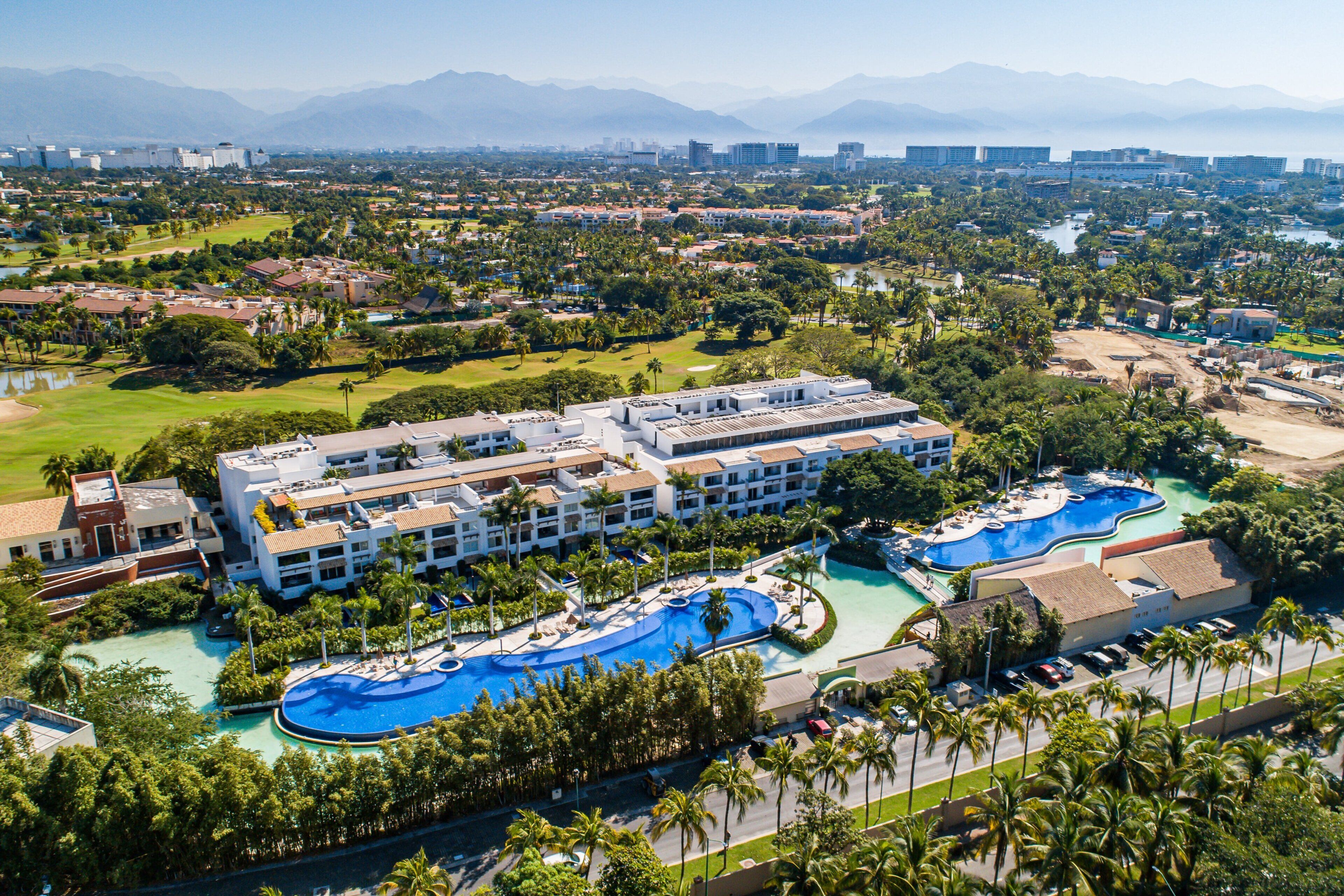 Een resort met meerdere zwembaden, weelderige begroeiing en een groot complex.