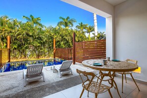 A poolside area with a table and chairs, a bench, and a view of a pool surrounded by palm trees. - Lovely Studio With Private Outdoor Pool, On-site Golf, Patio, & AC (Nuevo Nayarit)